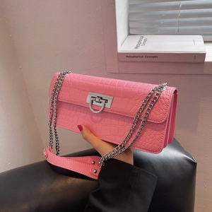 Detail of pink crocodile embossed leather texture and silver buckle on crossbody bag