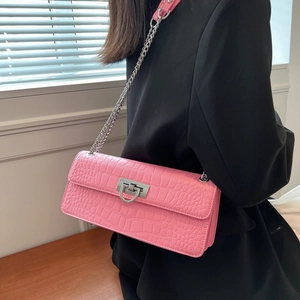 Detail of pink croc-embossed crossbody bag featuring a silver square clasp and chain strap