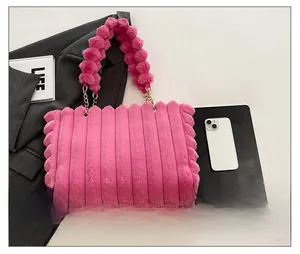 Detail of fuchsia plush striped shoulder bag with pom-pom handle and gold chain