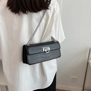 Detail view of black crocodile pattern crossbody bag with silver chain and metal lock