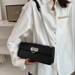 Close-up of black crocodile texture handbag with silver D-ring buckle and chain strap
