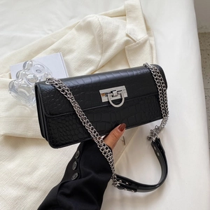 Detail of black crocodile pattern leather bag featuring a silver metal twist lock