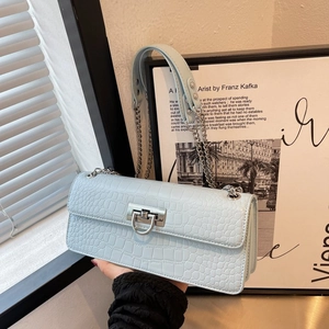 Close-up of light blue crocodile pattern bag with silver U-shaped metal lock and chain strap