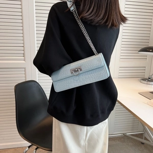Light blue croc-embossed shoulder bag with silver chain strap worn by a model