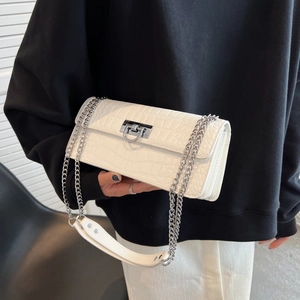 Detail of white crocodile texture bag featuring silver twist lock and chain strap