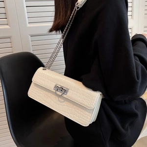 Close-up of cream crocodile pattern bag with silver chain strap on model shoulder