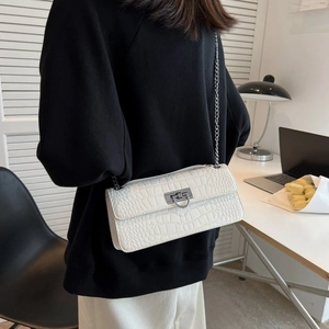 Detailed view of white crocodile pattern shoulder bag with silver metal chain and buckle