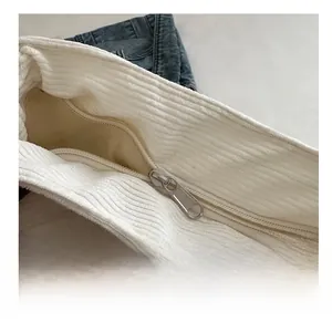 Gros plan sur la fermeture éclair en métal et la texture du velours côtelé blanc du sac