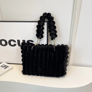 Macro detail of black fuzzy striped tote bag with plush pom-pom handle and gold chain link