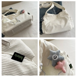 Détail du sac cabas en velours côtelé blanc avec écussons étoiles et breloques en peluche