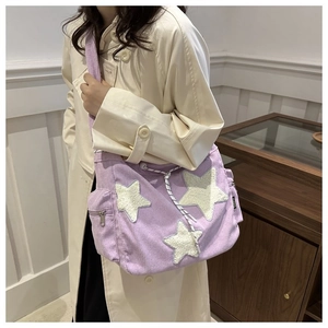 Détail du sac à bandoulière en velours violet avec étoiles en peluche et cordon de serrage