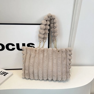 Close-up of plush striped tote with fluffy ball handle and gold metal chain links