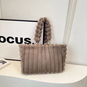 Detail of plush tote bag with striped texture and soft fluffy ball handle design