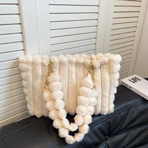 Detailed macro view of off-white faux fur tote bag with golden chain strap and plush ball