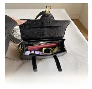 Top view of spacious interior of the black embossed leather handbag showing daily items