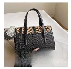 Detail showing high-quality black leather texture with leopard print flap on the tote bag