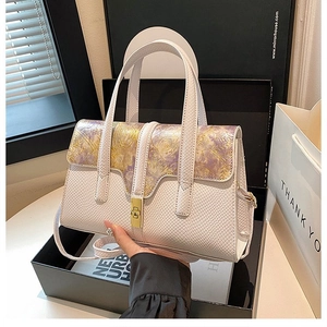 Detail of white leather handbag featuring purple floral pattern and gold turn-lock closure