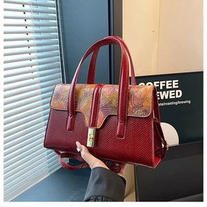Detail of red faux leather handbag featuring vintage floral embossing and metal clasp