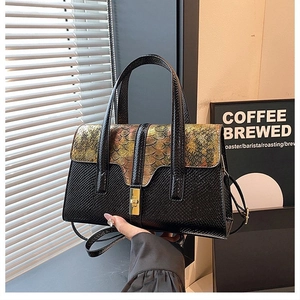 Detail of luxury black and gold shoulder bag with faux snakeskin texture and metal lock