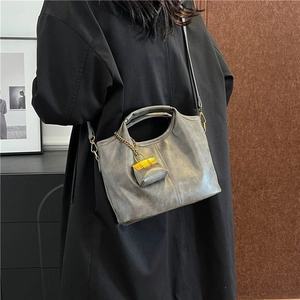 Vintage grey leather crossbody bag with matching pouch on model in a stylish indoor setting