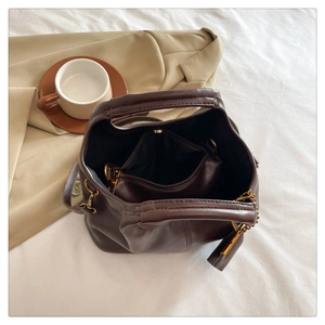 Deep brown matte leather handbag with inner compartments shown in cozy lifestyle setting