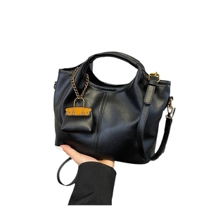 Classic black leather tote bag with round handles and a yellow mini bag charm decoration