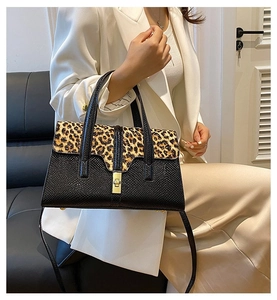 Detailed close-up of leopard print flap and textured lizard pattern faux leather on handbag