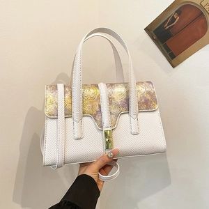 White snakeskin handbag with purple floral flap and gold metal lock held by a person