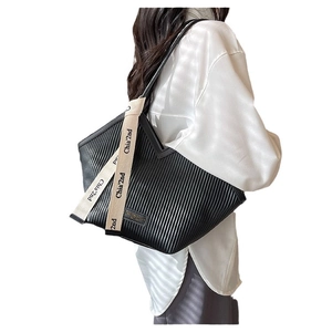 Winter black pleated tote bag with branded woven strap shown on model's shoulder