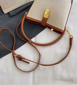 Detail of canvas bucket bag with brown leather trim and golden metal twist lock