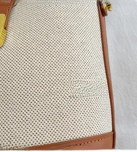 Detail of cream canvas fabric with brown leather trim and golden metal hardware