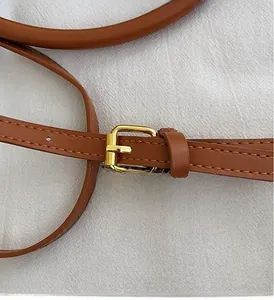 Detailed shot of tan leather strap with golden metal buckle and neat contrast stitching
