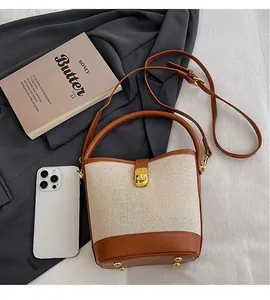 Detail of canvas and brown leather bucket bag showing golden twist lock and metal feet
