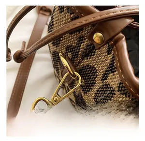 Detail of premium golden metal hook and drawstring on brown woven bucket bag