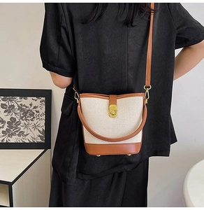 Detail of canvas and brown leather bucket bag shown on a model with golden twist lock