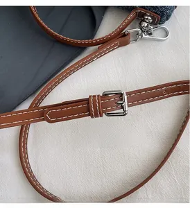Detail of brown leather strap with silver metal adjustment buckle and white stitching