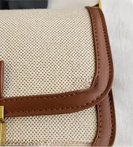 Close-up of woven canvas fabric with brown leather trim and detailed stitching on handbag