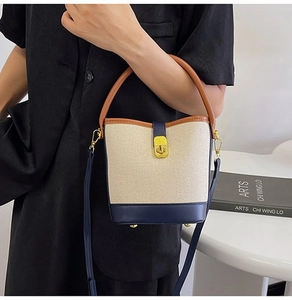 Detail of canvas bucket bag showing navy leather base and elegant gold metal lock
