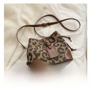 Close-up of leopard print drawstring bucket bag with brown leather base and strap detail