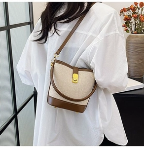 Detail of canvas bucket bag with brown leather trim and golden metal turn-lock on a model