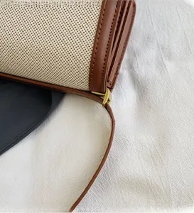 Detail of canvas and leather stitching with polished gold metal hardware on bag