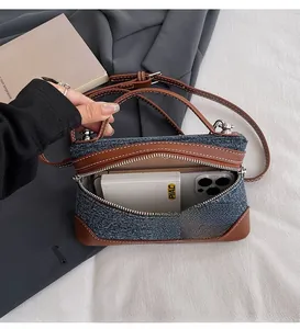 Detail showing inner capacity of denim shoulder bag with brown leather trim and contrast stitching