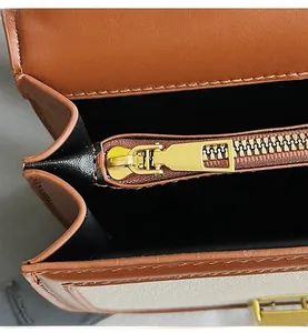 Detailed close-up of smooth gold metal zipper and stitching on brown leather handbag