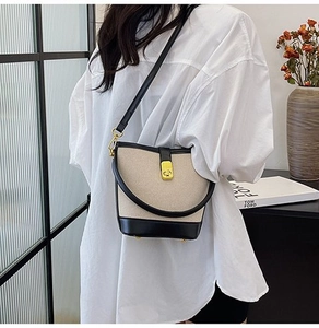 Detail of canvas bucket bag showing mixed leather textures and golden rotating lock