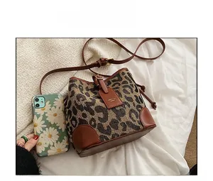 Detailed view of leopard print bucket bag with brown leather trim and drawstrings