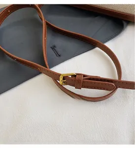 Macro view of adjustable brown leather shoulder strap with gold-tone buckle hardware