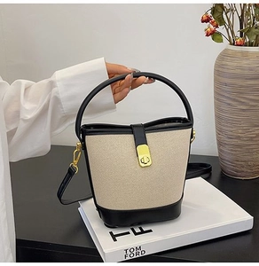 Detail of color-block bucket bag featuring canvas texture and elegant gold metal clasp