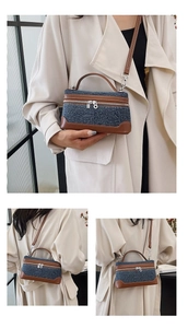 Close-up of contrast stitching on denim box bag with brown leather handles and silver zipper