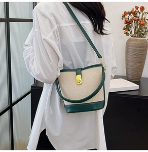 Detail of color-block canvas bucket bag with green leather trim and golden metal clasp