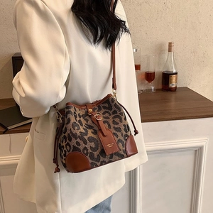 Detail of leopard print bucket bag with brown leather trim worn with a white blazer